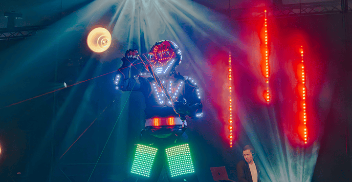 Tänzer mit LED-Platten-Kostüm und DJ auf der Bühne der Messeparty der Catering-Messe #essenz in Augsburg