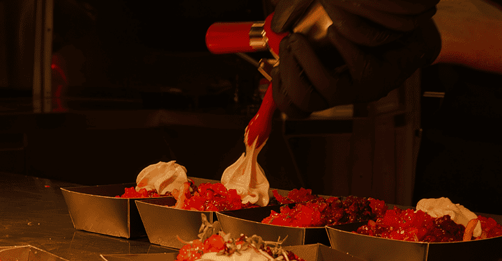 Ein Koch verziert mehrere Schälchen mit Streetfood beim Event-Catering auf der Catering-Messe #essenz in Augsburg