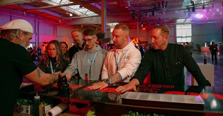 Mehrere Gäste und Caterer Markus Grein bekommen am Stand von Koch Ralf Jakumeit ein Dessert auf die Hand serviert