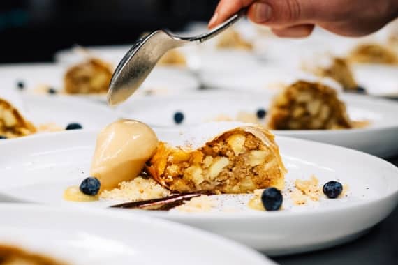 Ein Barista von Markus Grein richtet im Rahmen vom Barista-Catering in Nürnberg ein Dessert aus Apfelstrudel und Creme an.