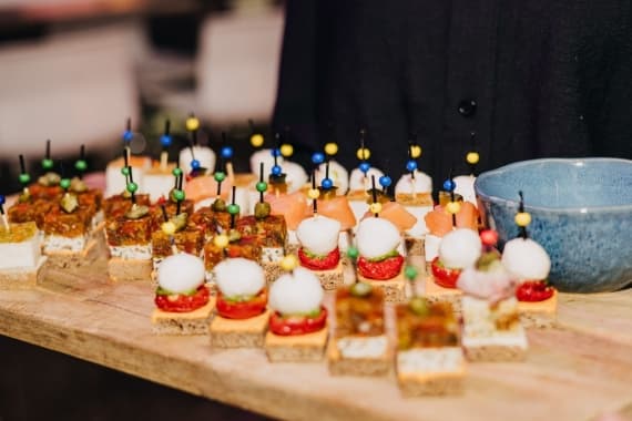 Holzbrett mit verschiedenen Canapés auf Spießen wird für Gäste auf einem Business-Catering bei einem Firmenevent serviert.