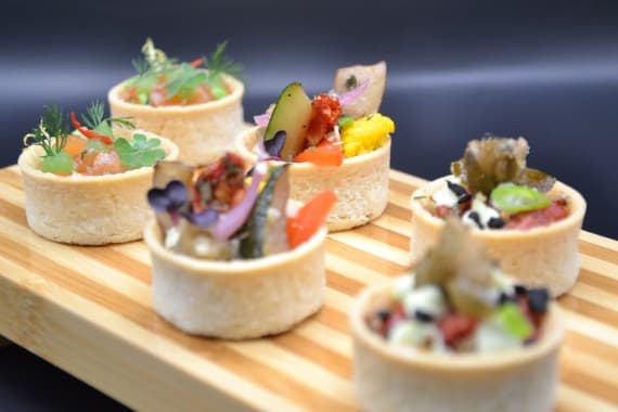 Verschiedene Desserts und Fingerfood mit Gemüse als Dekoration mit Gemüse und Kräutern stehen servierbereit.