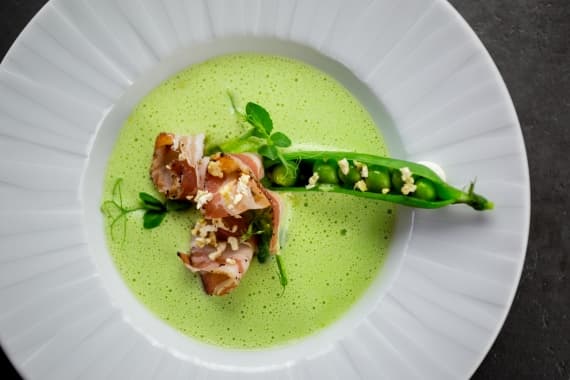 Ästhetisch angerichtete Erbsensuppe mit einer Erbsenschote bei einem Event mit Catering von Markus Grein.