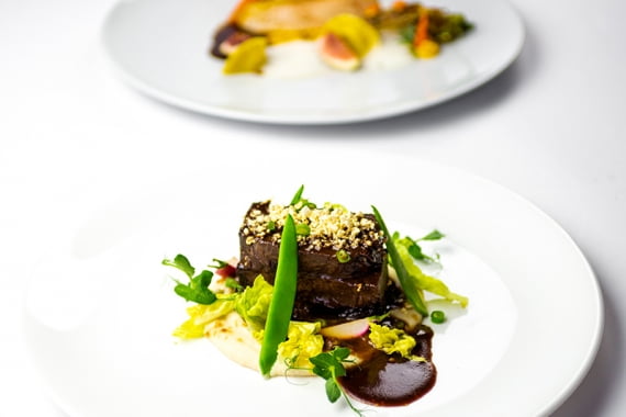 Von Markus Grein Catering stilvoll angerichtetes, geschmortes Fleisch mit Erbsen bei einem Event-Catering in Frankfurt.