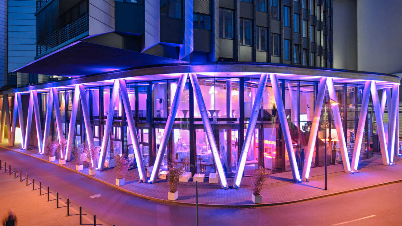 Lila beleuchtete Außenfassade der Frankfurter Eventlocation Westhafen Pier 1 am Abend.