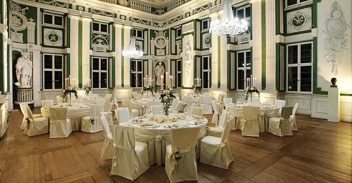 Festlich, traditionell eingerichteter Saal der Eventlocation Fürstliche Abtei in Amorbach mit Tischen und Stühlen mit Hussen.