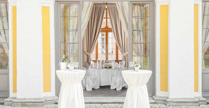 Cocktailtische im Außenbereich und festliche Einrichtung im Innenbereich der Eventlocation Gartenpavillon in Würzburg.