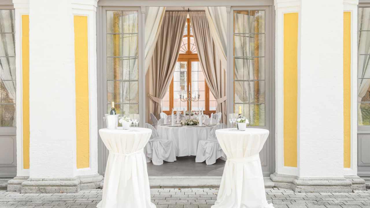 Cocktailtische im Außenbereich und festliche Einrichtung im Innenbereich der Eventlocation Gartenpavillon in Würzburg.