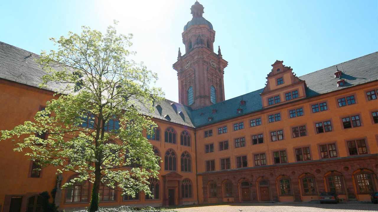 Innenhof der Eventlocation der Neubaukirche in Würzburg mit Blick auf den Kirchturm bei Sonnenschein und blauem Himmel.