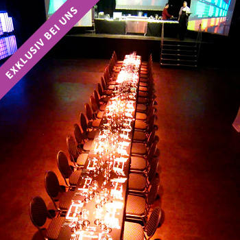 Vorbereitete lange Dinnertafel, noch ohne Gäste, bei einem abendlichen Firmenevent in Würzburg in der Eventlocation Posthalle.