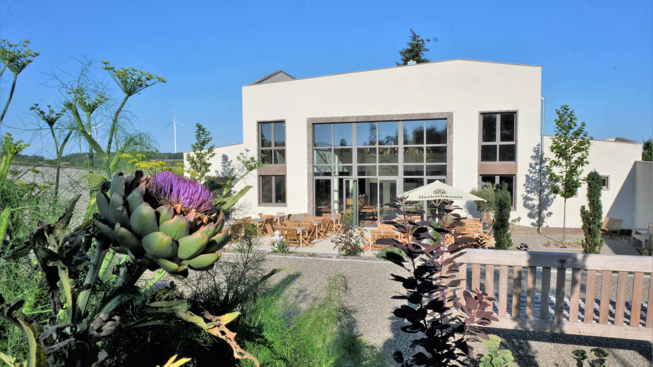 Außenbereich mit Blick auf die Eventlocation und Hochzeitslocation Villa Oriental in Ahorn im Hintergrund bei Sonnenschein.