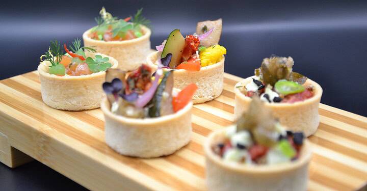 Sechs bunte Tartlets mit Gemüse und Kräutern stehen servierbereit bei einem Business-Event in Würzburg.
