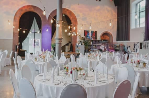Festlich dekorierte runde Hochzeitstische mit weißen Hussen und Hochzeit-Catering in Würzburg im Maschinenhaus