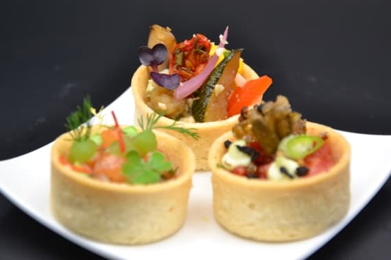Fingerfood mit belegten Mini-Tartelettes, frischem Gemüse und Obst, angerichtet bei einem Hochzeitscatering in Frankfurt.