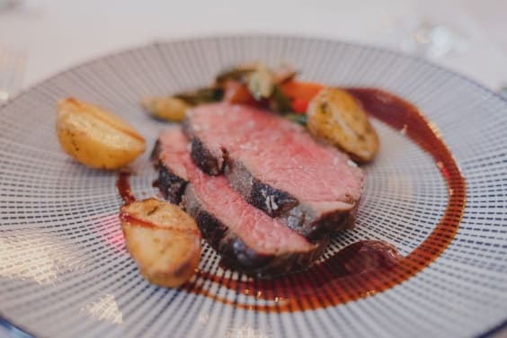 Hochzeitsessen in Würzburg von Markus Grein Catering mit rosa Rindfleisch, kleinen Kartoffeln und Gemüse.