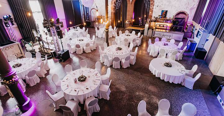 Hochzeitslocation in Würzburg Maschinenhaus Innenansicht mit mehreren runden Tischen für das Hochzeitsessen vorbereitet