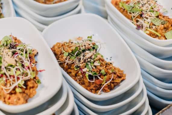 Mehrere kleine weiße Schalen mit herzhaftem Linsengericht und frischen Sprossen bei einem Buffet auf der Messe Frankfurt.