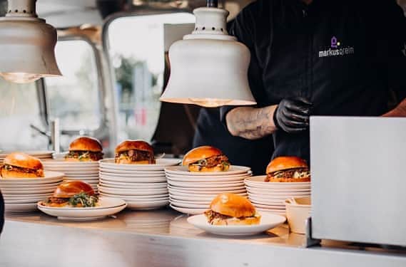 Mehrere Burger liegen servierbereit beim Foodtruck Catering auf der Theke vom Airstream von Markus Grein Catering.