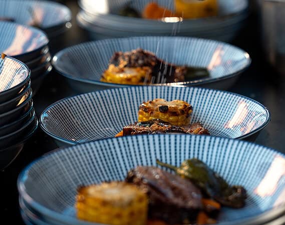 BBQ-Catering fein angerichtet in blauen Schalen Maiskolben