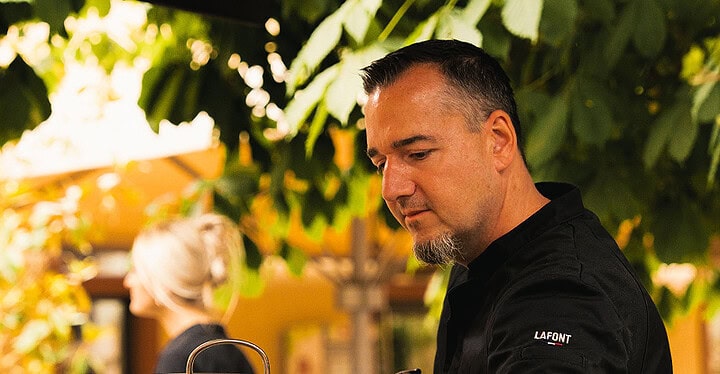 Koch bereitet im Freien frische Kräuter und Zutaten am großen Topf beim Event-Catering zu