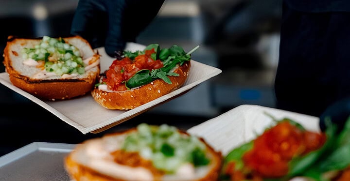 Burger mit Tomate und Rucola werden beim Foodtruck Catering frisch angerichtet
