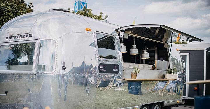 Streetfood-Catering mit einem Airstream-Foodtruck von Markus Grein Catering bei einem sommerlichen Outdoor-Event.