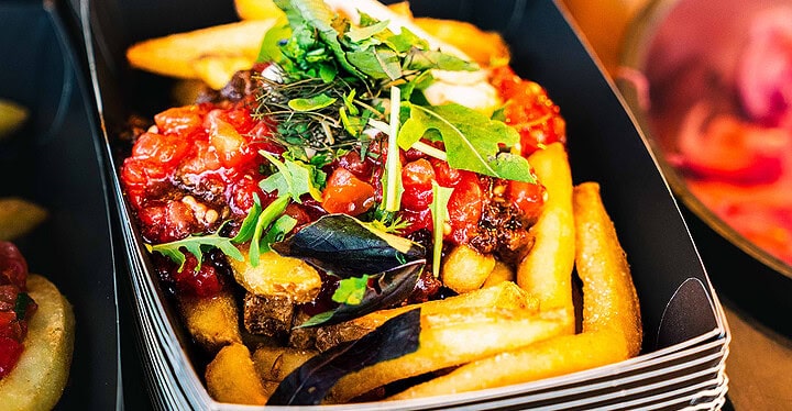 Loaded Fries mit Tomatensalsa und Rucola in der Pappschale beim Streetfood Catering
