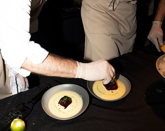 Koch mit Handschuh setzt ein Stück Rote Bete auf cremige Suppe in grauer Schale bei der Gastro Premium Night in Frankfurt