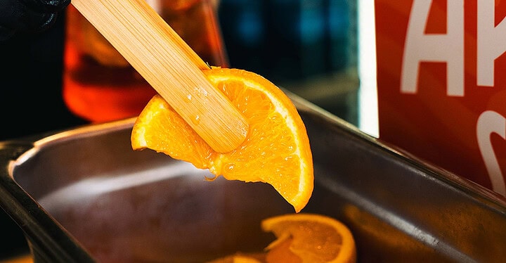 Nahaufnahme einer Orangenscheibe, die für Aperol Spritz zum Sektempfang vorbereitet wird