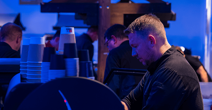 Barista stellt am Abend Kaffeebecher für Gäste einem abendlichen Messe-Catering bereit.