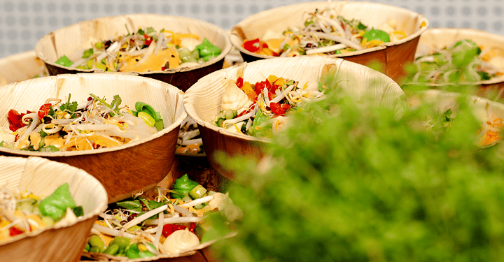 Kleine Salatschalen im Holzgeschirr für das Messe-Catering angerichtet.