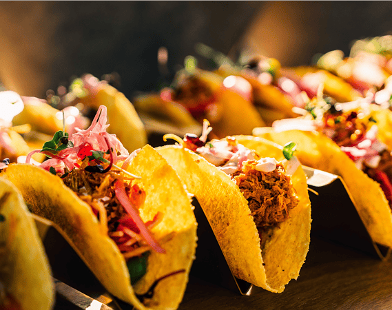 Bunt gefüllte Tacos aufgereiht auf dem Buffet beim Messe-Catering.