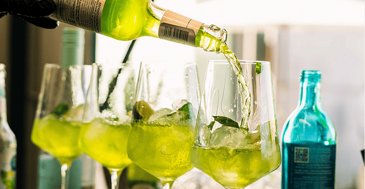 Bei einem Messe-Catering wird ein grüner Aperitif wird in Gläser für die Gäste eingeschenkt.