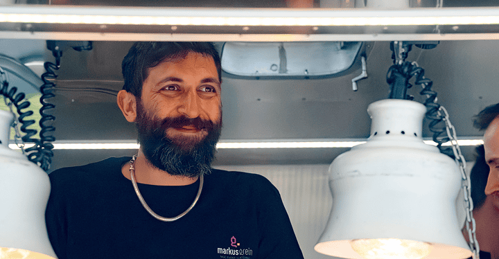 Lächelnder Koch steht im Foodtruck und kümmert sich um Grill & BBQ.
