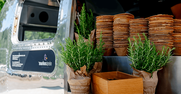 Foodtruck mit Streetfood und gestapeltem Geschirr und Pflanzen sind für eine Messe vorbereitet.