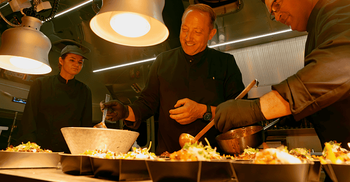 Kochteam bereitet konzentriert ein Buffet in einem Foodtruck vor.