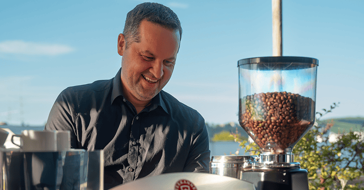 Lächelnder Barista arbeitet bei Messe-Catering konzentriert an der Espressomaschine.