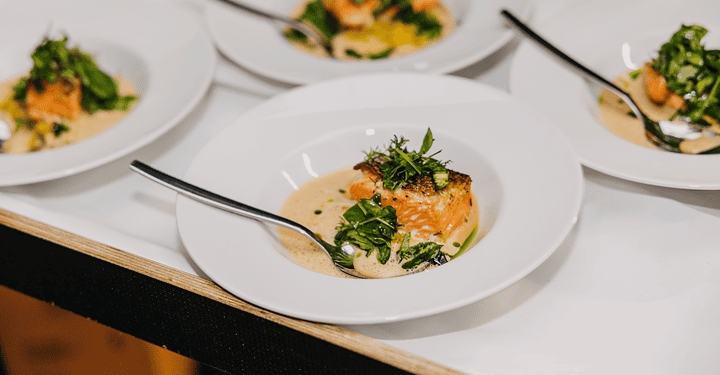 Angerichtete Lachs-Vorspeise auf weißen Tellern für ein Messe-Catering-Buffet.