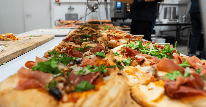 Pizza mit Schinken und Rucola wird bei einem Messe-Catering in der Küche zubereitet.