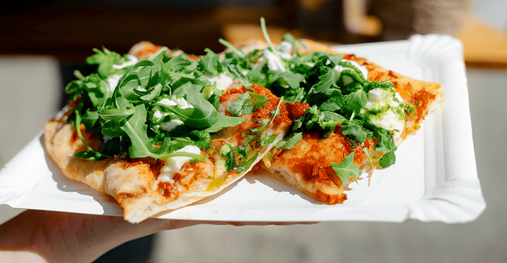 Frisch belegte Pizza mit Rucola bei einem Messe-Catering.