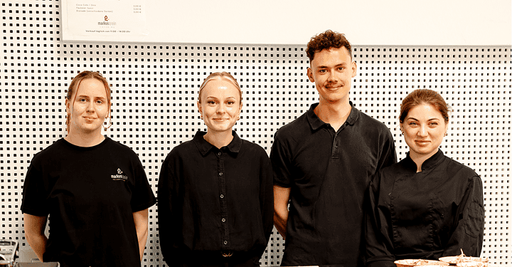 Vierköpfiges Serviceteam steht bereit vor dem angerichteten Buffet des Messe-Caterings.