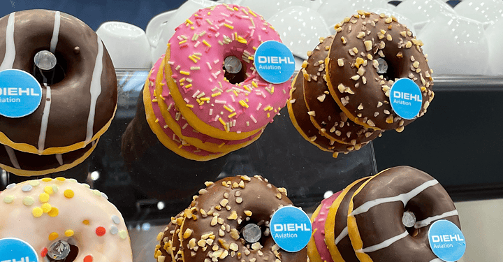 Bunt verzierte Donuts mit Firmen-Branding auf einer Etagere als süßes Angebot bei einem Messestand.