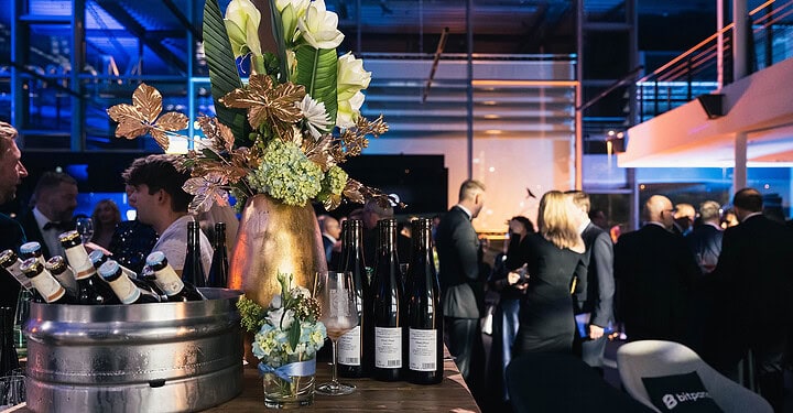 Stilvoll dekorierte Bar mit Blumenschmuck und Getränken bei der Messe-Standparty.