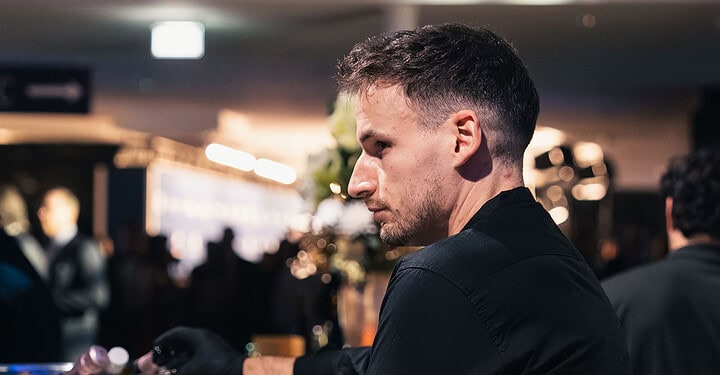 Barkeeper schenkt konzentriert Getränke für Gäste der Messe-Standparty aus.