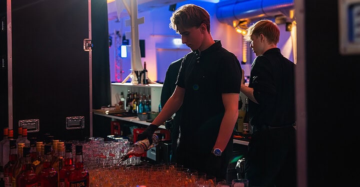 Barteam bereitet an der Bar Getränke für Gäste der Messe-Standparty vor.