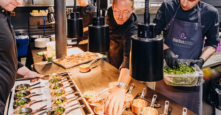 Vierköpfiges Küchenteam bereitet gemeinsam Speisen für das Messe-Catering vor.