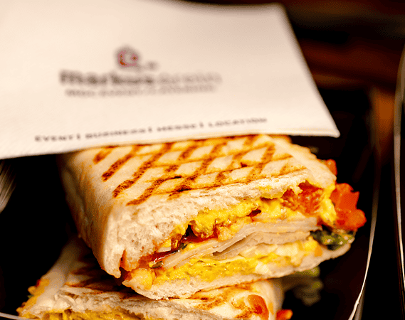 Gegrillte Panini-Sandwiches gestapelt neben einer Serviette mit Firmenlogo.