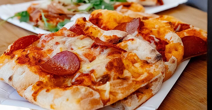 Pizza mit Salami und Pizza mit Parmaschinken und Rucola nebeneinander beim Pizza Catering für einee Hochzeit