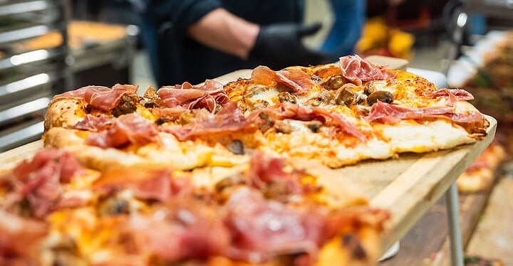 Frisch gebackene Salamipizza vom Blech beim Pizza Catering auf einer Hochzeit