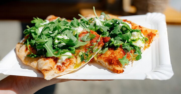 Frisch gebackene Pizza mit Rucola auf Pappteller aus dem Foodtruck